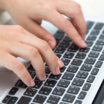 Close up of hands next to a keyboard